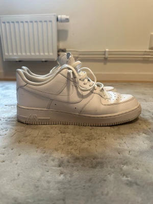 Nike Air Force 1 vita sneakers - PRIS KAN DISKUTERAS!!!. Lite förstörda där inne annars är dem bra!!!!.   Klassiska vita Nike Air Force 1 sneakers i lågt utförande. Skorna har en stilren design med perforerad tå, vita skosnören och Nike-logga på sidan och hälen. Tillverkade i läder med gummisula för bra grepp.