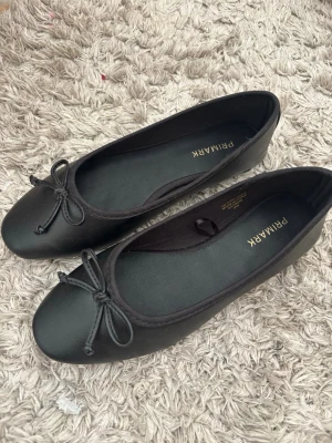 Svarta ballerinaskor  - Svarta ballerinaskor från Primark, med en rosett. I storlek 35 men passar mig och jag har 36.