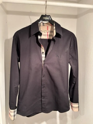 Svart burberry skjorta  - Säljer min svarta burberry skjorta i storleken M. Väldigt bra skick, knappt använt eftersom jag har så mycket skjortor och jätte mycket pengar(jätte rik).Billigare vid snabb och smidig försäljning. Skriv gärna för frågor. Mvh Pontus.