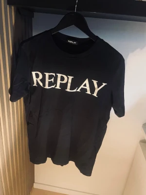 Svart t-shirt från Replay - Säljer en svart t-shirt från Replay med stor vit logga framtill. . Perfekt basplagg med stilren design som passar till det mesta. Pris kan diskuteras vid snabb affär 