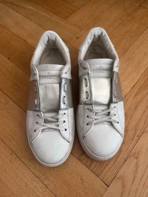 Valentino open - Ett par silvriga valentino open i befintligt skick. De är använda men är fortfarande fina och har absolut mycket kvar att ge. De är i storlek 42 och är självfallet äkta. Passar både killar såväl som tjejer. Det ärbara att höra av sig vid frågor eller funderingar