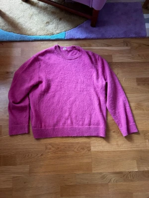 Rosa stickad tröja med rund hals - En enkel och snygg rosa stickad tröja med rund halsringning och ribbade muddar vid ärmslut och nederkant. Perfekt för dig som gillar färg och vill ha något mjukt och bekvämt i garderoben.