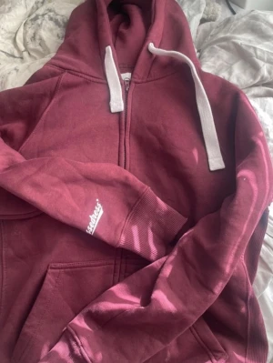 Vinröd russemerch hoodie  - Säljer min russemerch zip hoodie, knappt använd. Storlek M