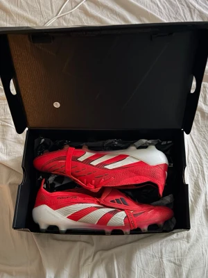 Adidas Predator fotbollsskor - Säljer ett par röda Adidas Predator Elite i färg röd/vit. Skorna har AG dobbar, men funkar även på naturgräs. De är överlag i okej/bra skick. Inga defekter, men det syns att de är använda. Orginalbox ingår✅ Ordinarie pris: 2700. Mitt pris: 499