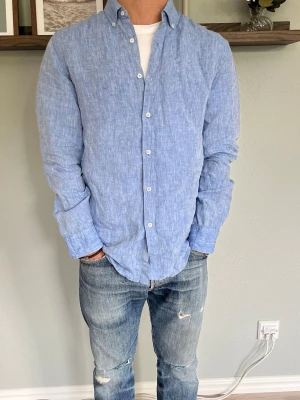 Mango Man Linneskjorta Ljusblå S - Mango Man skjorta i 100% linne, ljusblå melerad färg. Klassisk button-down-krage, knappstängning fram. Lätt och luftig, perfekt för vår/sommar.  Skick: bra skick, inga hål eller fläckar Material: 100% linne Storlek: EUR S  Modell: 175 cm / 65 kg — sitter true to size på bild