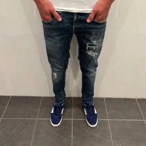 Dondup Jeans George  - Dondup Jeans George! Trendigaste jeansen på marknaden.  Skick= 9/10 Ny pris= 4000 kr Säljs för= 1199 kr (Modellen har original slitningar från fabrik vilket är väldigt eftertraktat och populärt)