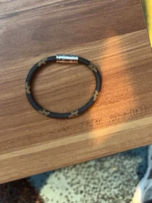 Svart armband med knutar - Snyggt svart armband i repmaterial med flera dekorativa bruna knutar och ett stilrent magnetlås i metall. Perfekt accessoar för dig som gillar en enkel men cool look.