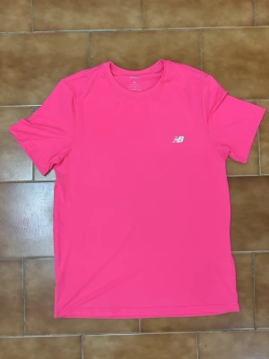 New Balance träningsset  - Säljer ett sportigt träningsset från New Balance med en rosa t-shirt och svarta shorts. Otroligt snygg set. T shirten säljs för 500kr. Shorts 300kr. Hela settet 700kr.