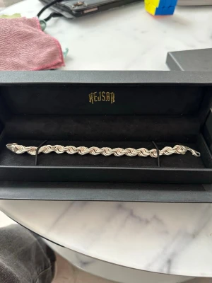 Silverfärgat armband från Kejsar - Säljer ett stilrent armband och kedja från Kejsar i silverfärg. Armbandet och kedjan har en tvinnad kedjedesign som ger en exklusiv känsla och passar perfekt till dig som gillar att sticka ut. Låset är robust och smycket levereras i original ask.