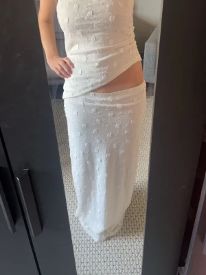 Vitt set - Säljer en vit långkjol med en  oneshoulder topp till. Setet har ett blommigt mönster och är figurnära🌸somrigt o fint, använt en gång