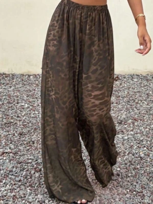 Bruna vida byxor med leopardmönster - Säljer ett par bruna byxor med leopardmönster och breda ben. Byxorna har resår i midjan och är tillverkade i ett tunt, luftigt material som passar perfekt till sommaren. De har en avslappnad och trendig look. 
