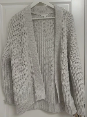 Beige stickad kofta - En beige stickad kofta med tillhörande skärp från H&M. Detta värmer väldigt mycket är passande både för hösten och vintern