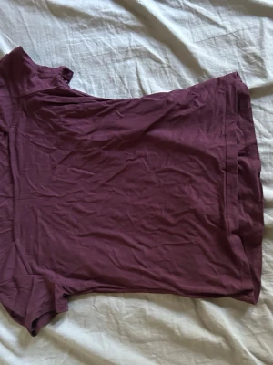 Mörklila basic t-shirt - En enkel mörklila t-shirt i mjukt bomullstyg. T-shirten har korta ärmar och en klassisk rund halsringning. Perfekt att matcha med jeans eller shorts för en avslappnad look.