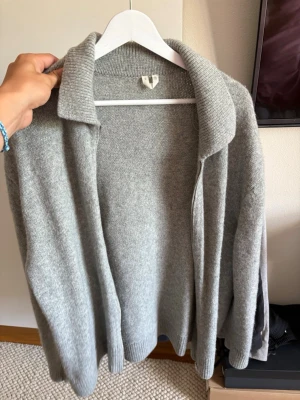 Arket overshirt  - Mysig ljusgrå kofta i mjukt stickat material. Koftan är öppen framtill och har en bred krage som ger en avslappnad look. Perfekt att slänga över en t-shirt eller topp för extra lager. Passar till både jeans och kjol.