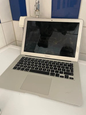 MacBook Air 13-tum silver - Säljer en stilren MacBook Air med 13-tums skärm i klassisk silverfärg. Datorn har ett tunt och lätt aluminiumchassi, svart tangentbord och stor styrplatta. Perfekt för studier, surf och kreativt arbete. Apple-loggan lyser på locket. Datorn fungerar ej då ssd är ej möjlig att komma åt. Även gångjärnet på skärmen orkar inte hålla uppe skärmen själv