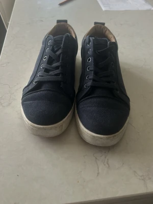 Mörkblå sneakers med vit sula - Snygga mörkblå sneakers med klassisk låg profil och vita sulor. Skorna har textilöverdel, matchande mörkblå skosnören och ljusbrunt innerfoder. Perfekta för en stilren och avslappnad look.
