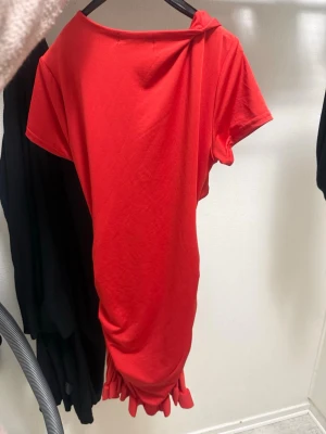 Röd kortklänning med snörning - Säljer en röd kortklänning från SHEIN med coola snörningsdetaljer framtill och korta ärmar. Klänningen har en unik design med drapering och knytband som ger en trendig look. Perfekt för dig som vill sticka ut!