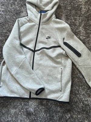 Ljusgrå hoodie från Nike - Säljer en stilren ljusgrå hoodie från Nike. Hoodien har en klassisk huva och är gjord i mjukt sweatshirtmaterial som är perfekt för chill dagar. Enkel design utan tryck eller mönster, passar till det mesta i garderoben.
