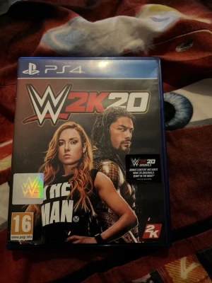 WWE 2K20 PS4 spel - WWE 2K20 till PlayStation 4 är ett actionfyllt wrestling-spel med realistisk grafik och kända brottare på omslaget. Omslaget är färgstarkt med svart, röd och vit text och spelet kommer i ett klassiskt blått PS4-fodral.