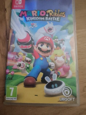 Mario + Rabbids Kingdom Battle Switch - Nintendo Switch-spelet Mario + Rabbids Kingdom Battle där Mario och Rabbids samarbetar i ett färgglatt strategispel. Omslaget är färgstarkt med Mario och Rabbids-karaktärer i tecknad stil. Perfekt för dig som gillar äventyr och strategi.