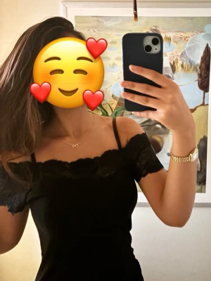 Svart offshoulder topp med spets - Säljer en svart offshoulder topp med tunna axelband och fina spetsdetaljer längs kanten. Toppen har en figurnära passform och är perfekt för dig som vill ha en stilren men ändå romantisk look.