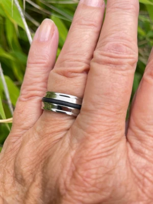 Stilren silverfärgad ring i rostfritt stål med svart detalj - Säljer en snygg och modern ring i silverfärgad rostfritt stål med en svart rand i mitten. Ringen har en slät, blank yta och en stilren design som passar till många olika looks. Perfekt för dig som gillar minimalistiska accessoarer. Italiensk design som levereras i en smyckesask. Storlek 18 mm