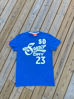 Superdry t shirt ~ Vintage  - Säljer denna Superdry t shirt i mycket bra skick och som är Vintage. Storlek M. Passar perfekt för dig som är mellan 175-180! Hör av er vid frågor eller minsta fundering 🙌  Längd: 69,5 cm  Bred: 47,5 cm  Ärm: 18,5 cm