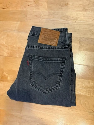 Levi's 511 - Snygga grå jeans från Levi's modell 511 med klassisk femficksdesign och slim passform. Jeansen har en tydlig läderpatch bak i midjan och den ikoniska röda Levi's-taggen på bakfickan. Tillverkade i slitstark denim, perfekta för en avslappnad stil. W28 och L30 som man ser på bild 1.