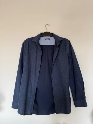 Mörkblå overshirt/skjorta - Mörkblå långärmad skjorta med något grövre/texturerat material. Stilren och passar både vardag och lite finare outfits. Funkar både som en skjorta och som en slags overshirt.