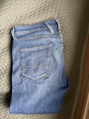 Replay anbass - Snygga blå slim fit jeans i klassisk femficksmodell med ljus tvätt och diskreta slitningar. Jeansen har normal midja och raka ben. Tillverkade i mjukt denimtyg som ger en bekväm känsla och passar perfekt till vardagslooken.