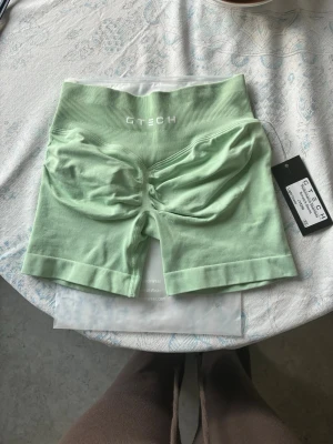 Light green performance seamless shorts  från GTECH - Snygg mintgrön seamless body från GTECH med hög midja och ribbad linning. Materialet är stretchigt och mjukt, med rynkade detaljer framtill för en snygg passform. Perfekt för dig som vill ha bekväma och trendiga underkläder.