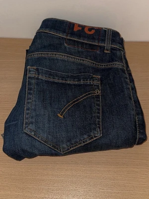 Mörkblå raka jeans från dondup - Säljer ett par klassiska mörkblå jeans i rak modell med kontrastsömmar och bakficka med broderad detalj. Jeansen är tillverkade i slitstarkt denimtyg och har en tidlös look som passar till det mesta.