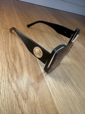Solglasögon - Eleganta solglasögon med stor fyrkantig form och mörka tonade glas. Det finns små repor på glasen (se bild), därav säljs de billigt