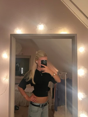 Svart croppad topp med knyt i ryggen - Svart croppad kortärmad topp med en super söt knytning i ryggen! Toppen är från Nelly i storlek xs. Den är perfekt för en basic outfit med plain jeans på hösten 🍂 Säljer pga att den inte kommer till användning 💞