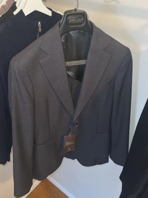 Mörkgrå kavaj från Oscar Jacobson - Stilren svart/mörkgrå blazer från Oscar Jacobson.  Jackan är aldrig använd så lapparna är fortfarande kvar. Storlek 48