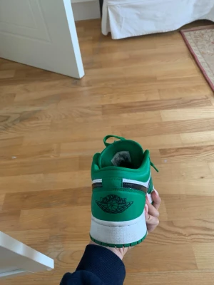 Gröna och vita Nike Air Jordan 1 Low  - Säljer ett par Nike Air Jordan 1 Low sneakers i grönt och vitt med svart swoosh. Skorna har klassisk snörning och låg profil. Perfekta för dig som vill sticka ut med en färgstark sneaker. Ikonisk Air Jordan-logga på hälen och tålig yttersula.