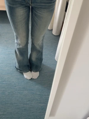 Ljusblå bootcut jeans - Säljer ett par ljusblå bootcut jeans med klassisk femficksdesign och dragkedja. Jeansen har en lätt utsvängd passform nedtill och är tillverkade i mjukt denimtyg. Perfekta för en avslappnad och trendig look. Fläken är en gräs fläk tror jag och går säkert bort i tvätten kan tvätta innan jag skickar!💕annars är dom som nya 💕💕