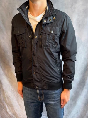 J-Lindeberg Fieldjacket - Stl S - Riktigt snygg Vår/Höst Fieldjacket från J-Lindeberg i färgen svart! | Mycket bra skick: 9/10, inga defekter | Stl: S, modellen är 178cm och väger ca 78kg 🙌Passar dock längre 166-178cm  | Hör av dig vid frågor // Galgen 🫡