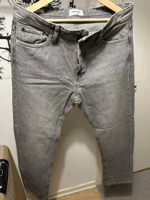 Grå jeans från Jack & Jones - Oanvända, Snygga grå jeans från Jack & Jones i klassisk femficksmodell. Jeansen har raka ben, normal midja och är tillverkade i ett mjukt denimtyg. Passar perfekt till en avslappnad streetwear-look.