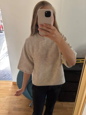 Beige stickad tröja med trekvartsärm - En enkel och stilren beige stickad tröja med trekvartsärmar och rund hals. Tröjan har en loose och skön passform. Använd ett par gånger men finns inga skador.