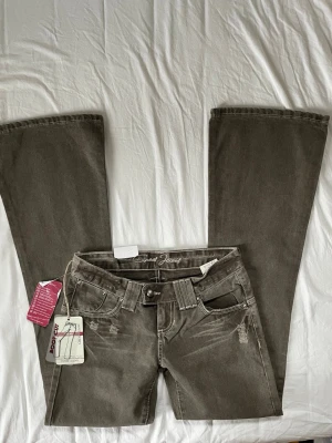 Vintage lågmidjade khaki jeans  - Jättesnygga och unika vintage bootcut jeans med lappar kvar i en khaki grön färg. Strl 26 (passar som XS) // midja 36cm tvärsöver, innerbenslängd 81,5cm 