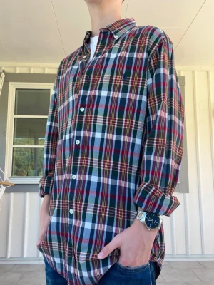 Rutig långärmad skjorta i bomull Ralph Lauren - Säljer en klassisk rutig skjorta i bomull med långa ärmar och knappar framtill. Skjortan har en mix av färger som röd, grön, blå och vit, samt en avslappnad passform. Perfekt för dig som gillar en tidlös och casual stil.