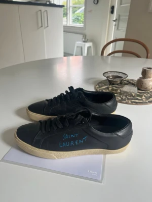 Saint Laurent Sneakers - Skor från Saint Laurent | Storlek: 39 kan passa 40 | Färg: Svart med mörkblå text | I fint skick | Skriv vid frågor |