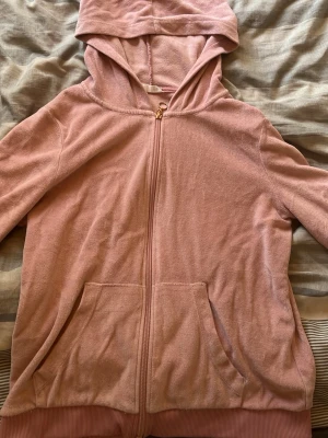 Rosa zip hoodie i mjuk frotté - Mysig rosa hoodie med dragkedja framtill och två stora fickor. Tillverkad i mjuk frotté som känns skön mot huden. Huva med dragsko och ribbade muddar vid ärmslut och nederkant. Perfekt för chill dagar eller som ett extra lager.