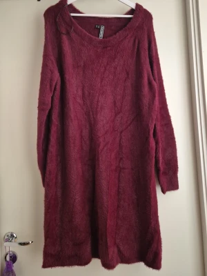 Vinröd klänning - Mysig vinröd klänning med lång ärm och rund halsringning. Klänningen har en fluffig och mjuk textur som ger en avslappnad och trendig look. Perfekt för kyligare dagar och enkel att styla med boots eller sneakers.