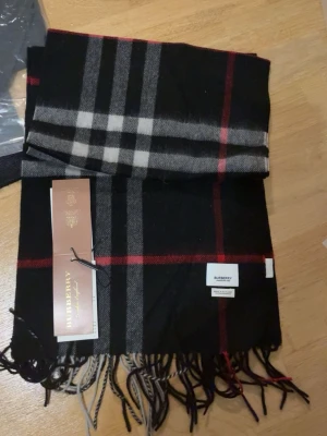 Rutig svart halsduk - Snygg svart halsduk  med klassiskt rutmönster i svart, vitt och grått. Halsduken har fransar i ändarna och är tillverkad i mjukt material. Perfekt accessoar för att lyfta din outfit speciellt när vintern närmar sig 🙃