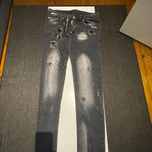 Svarta skinny jeans från Dsquared2 - Säljer ett par svarta skinny jeans från Dsquared2 med slitna detaljer och rätt så använda Jeansen har en silverfärgad dragkedja framtill, priset är diskuterbart! (Kan även byta mot andra plagg om intressant!)
