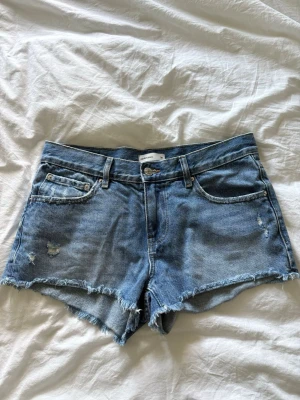 Lågmidjade jeansshorts  - Blåa lågmidjade jeansshorts från Ginatricot i storlek 36. Knappt använda.