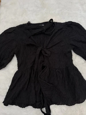 Svart knytblus från Gina Tricot - Trendig söt svart blus man knyter framtill från Gina Tricot i storlek XS. 