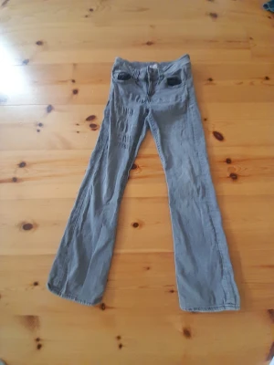 Grå bootcut jeans med fickor - Snygga grå jeans med bootcut passform och klassiska fem fickor. Jeansen har normal midja och dragkedja med knapp framtill. Materialet ser ut att vara bomullsdenim med lite stretch för extra komfort. Perfekta för en avslappnad och trendig look.